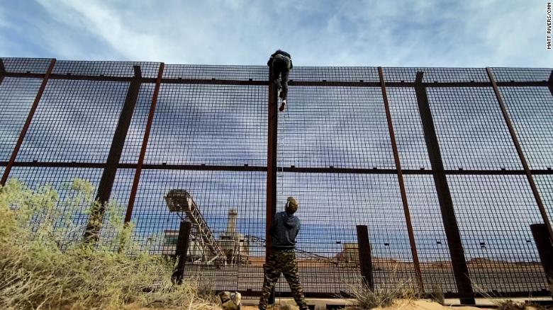 Migrante de Ecuador pasando el muro fronterizo entre Estados Unidos y México mientras un traficante de personas sostiene la escalera / CNN