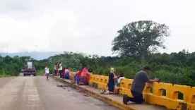 Ciudadanos se arrodillan y oran en uno de los puentes del Canal Maya en La Lima