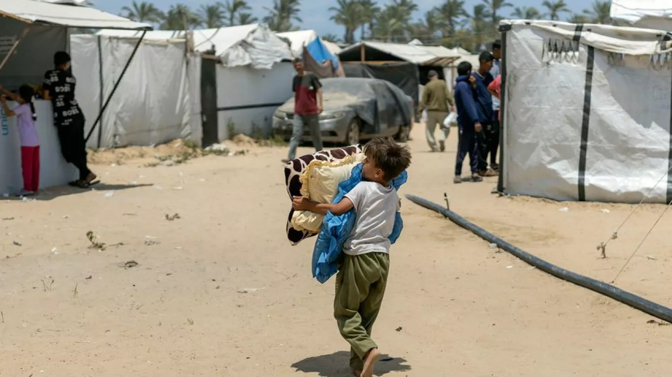 Un niño lleva sus pertenencias en el campo de desplazados de Al Mawasi, en Gaza.